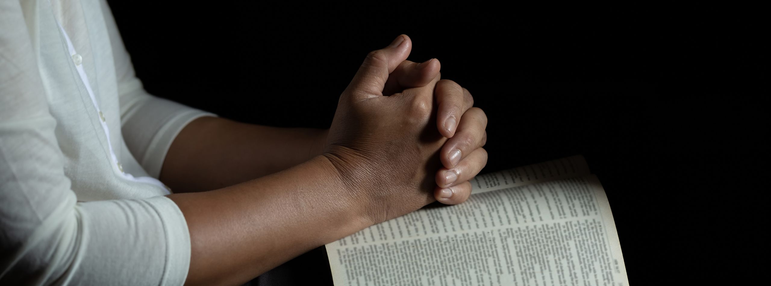 Hands folded in quiet reflection showing how to pray the Lord's Prayer with intention