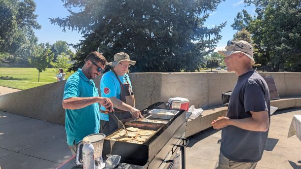 Men making pancakes at outdoor grill